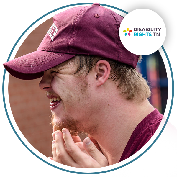 An image of a young man smiling with a maroon hat