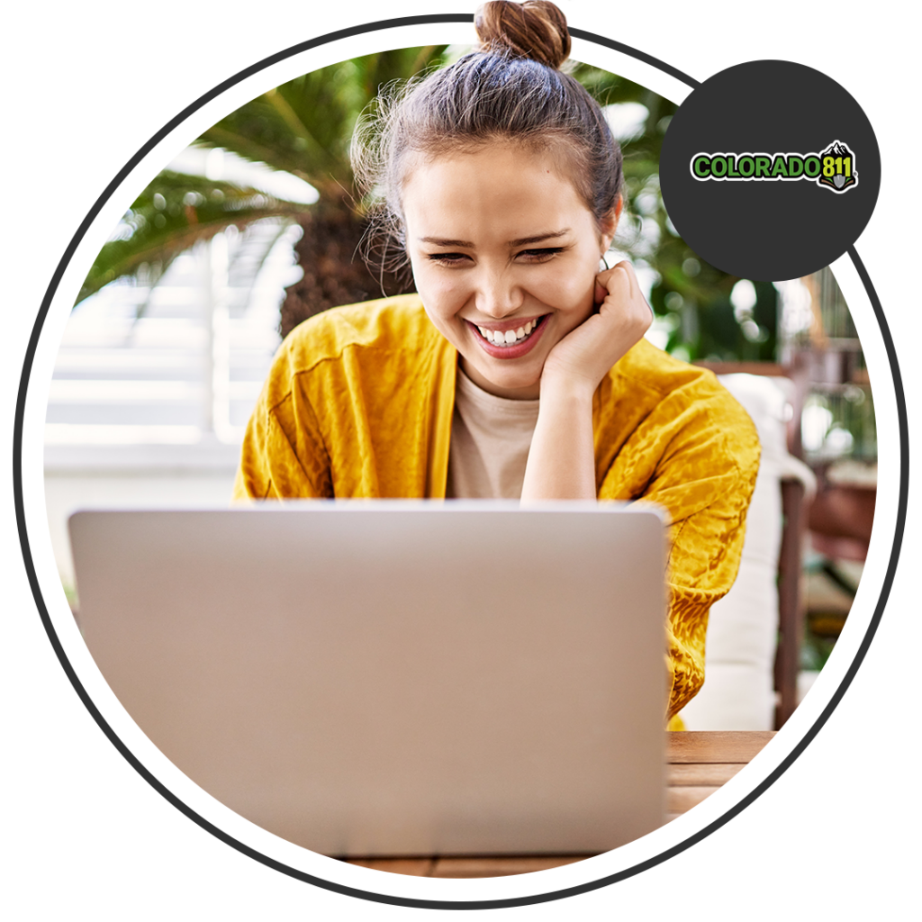 Image of a young woman wearing a yellow top smiling while looking at her laptop