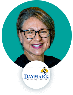 Image of a woman wearing glasses smiling on a teal background with the Daymark Recovery Services logo at the bottom