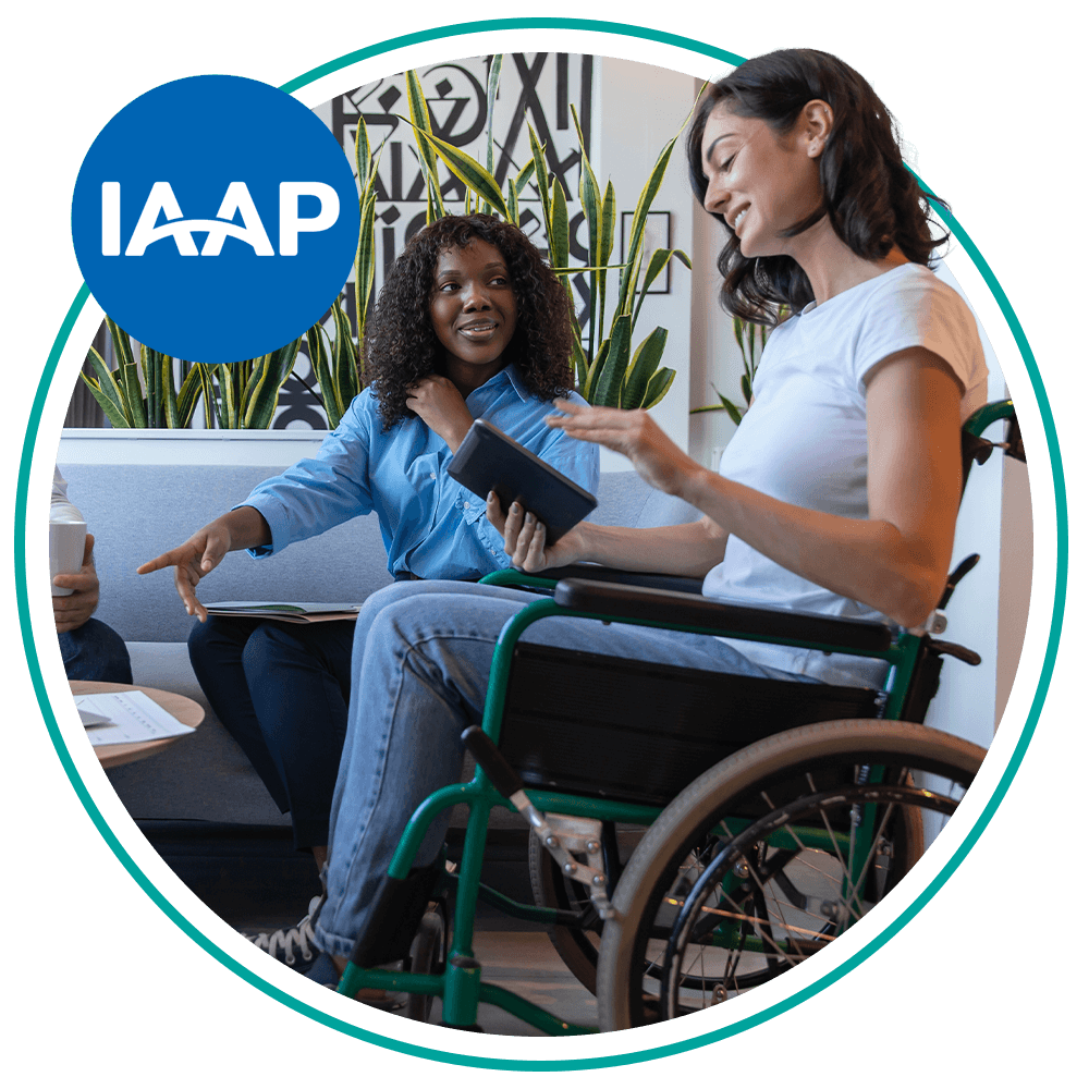 Image shows a wheelchair user using a tablet speaking to another person.