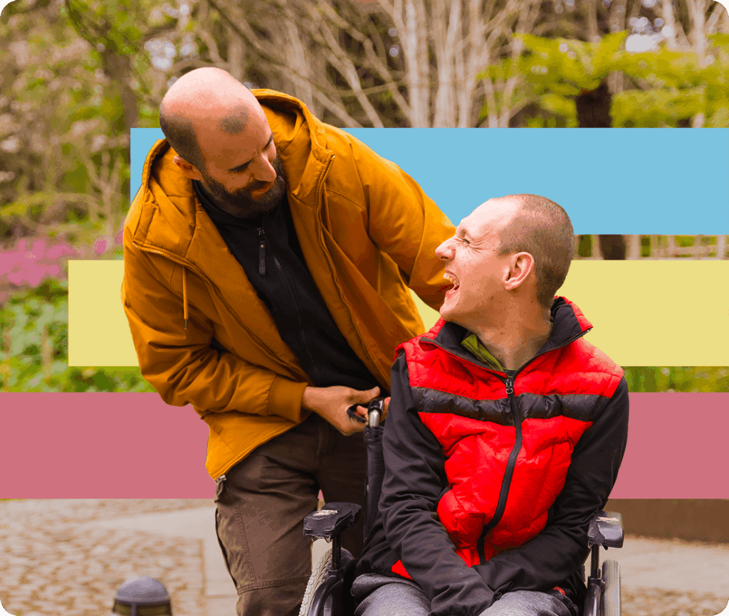 Man pushing another man in a wheelchair in a public park