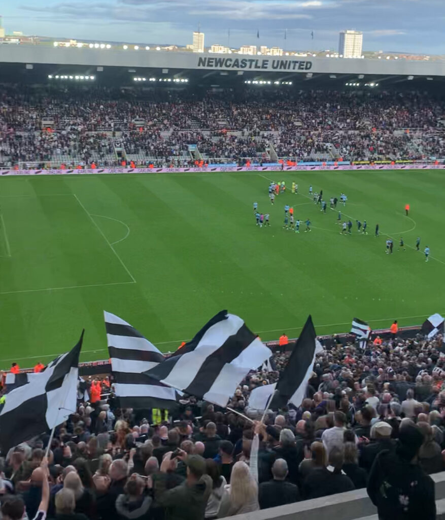 The football pitch with the crowd waving black and white flags