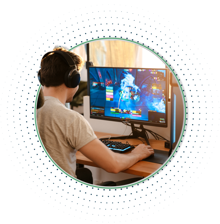 A young gamer sitting at his desk in front of a monitor playing games.