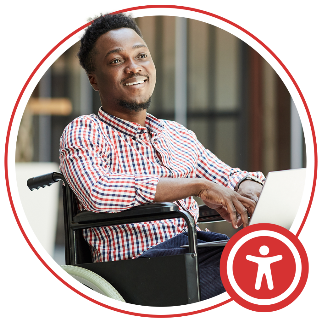 man sitting in wheelchair typing on laptop and smiling