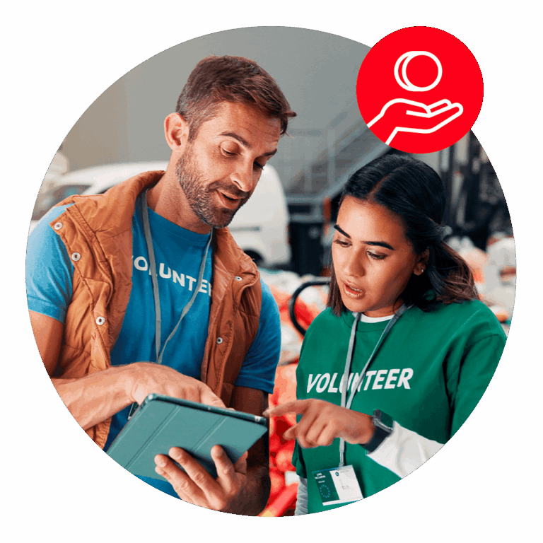 Two volunteers looking at and pointing to a tablet, with a red donation icon above them.